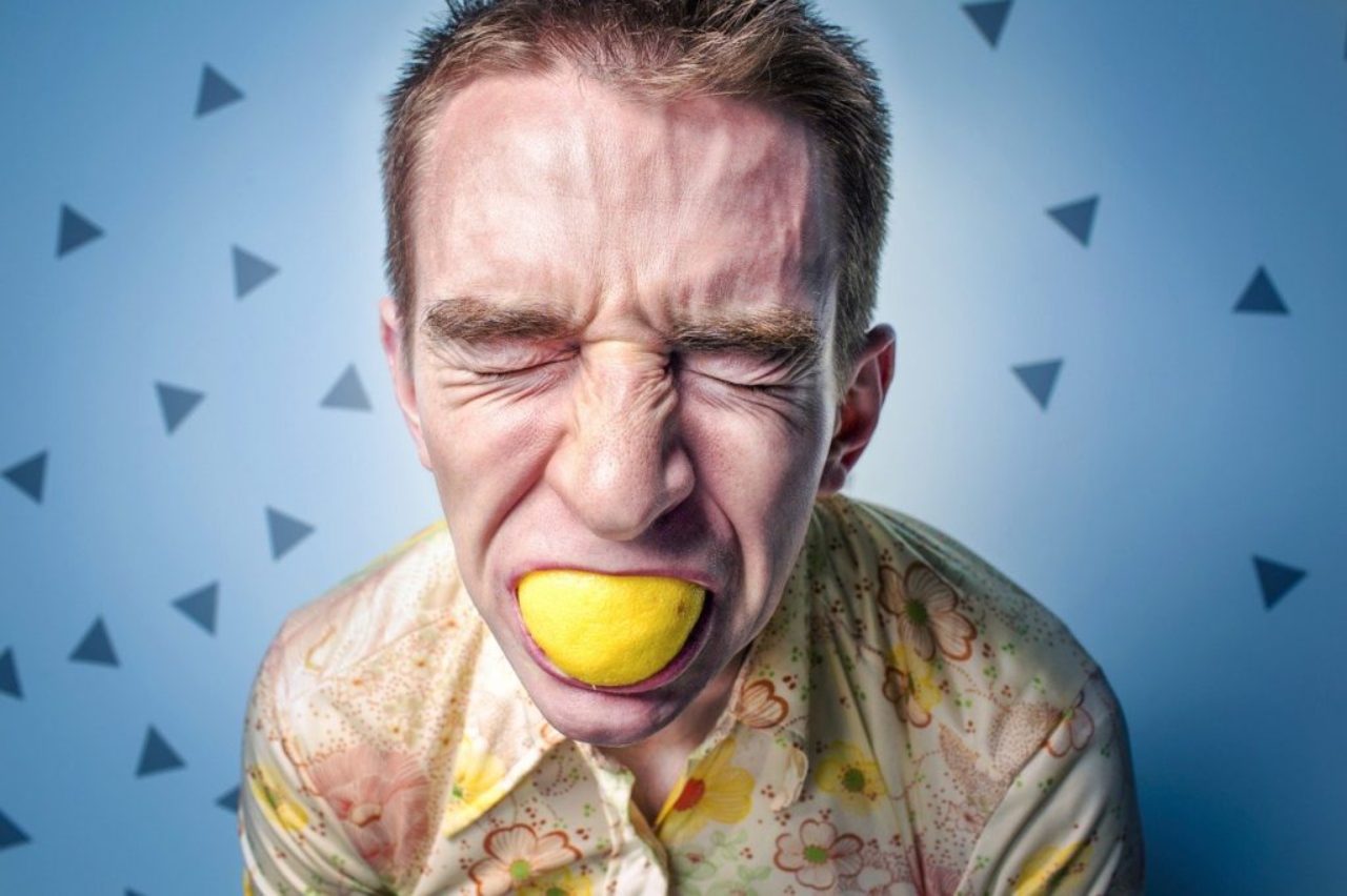 young-male-adult-stressed-face-with-lemon-fing-in-mouth