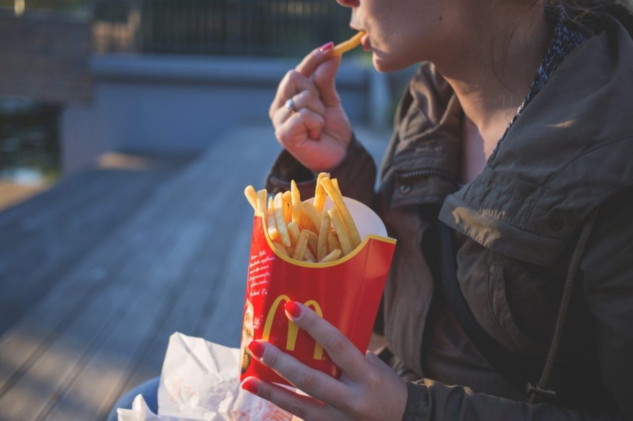 woman-in-brown-classic-trench-coat-eating-mcdo-fries-during