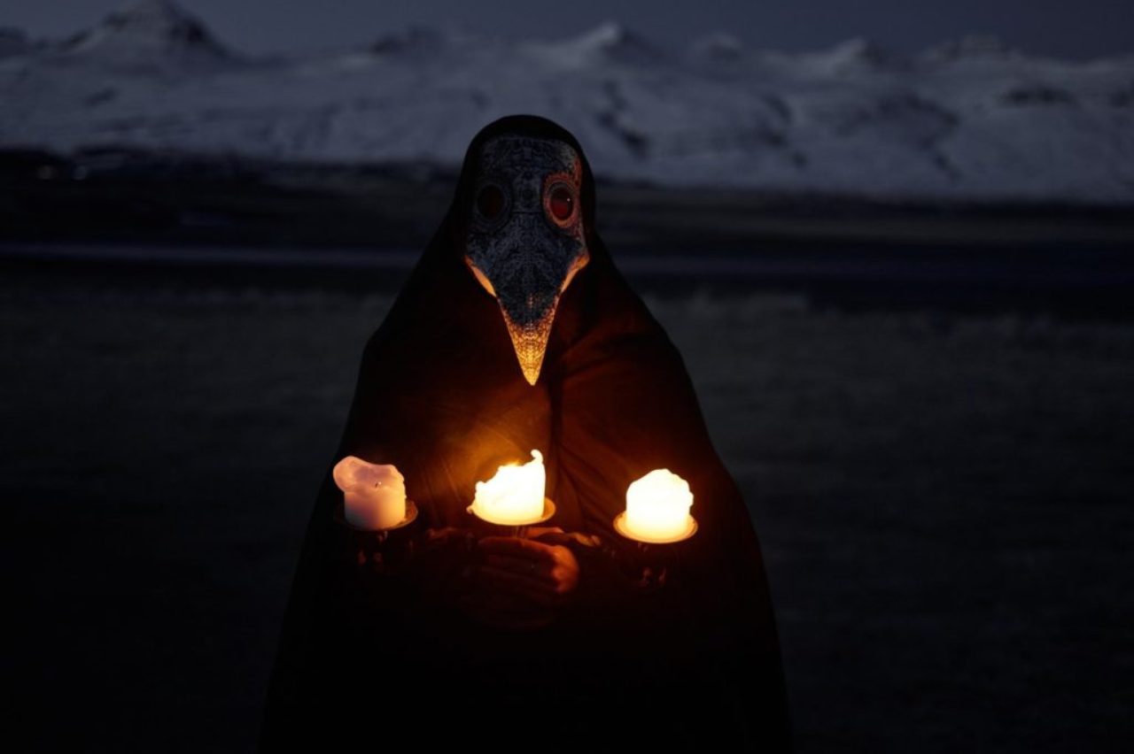 person-in-plague-mask-with-burning-candles-at-night-outdoors-4311150