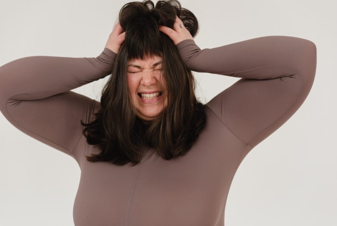 photo/young-obese-woman-rumpling-hair-with-closed-eyes-in-white-studio