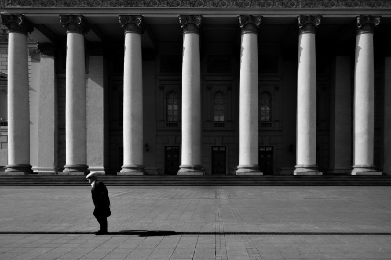 unrecognizable-citizen-against-old-urban-building-with-colonnade