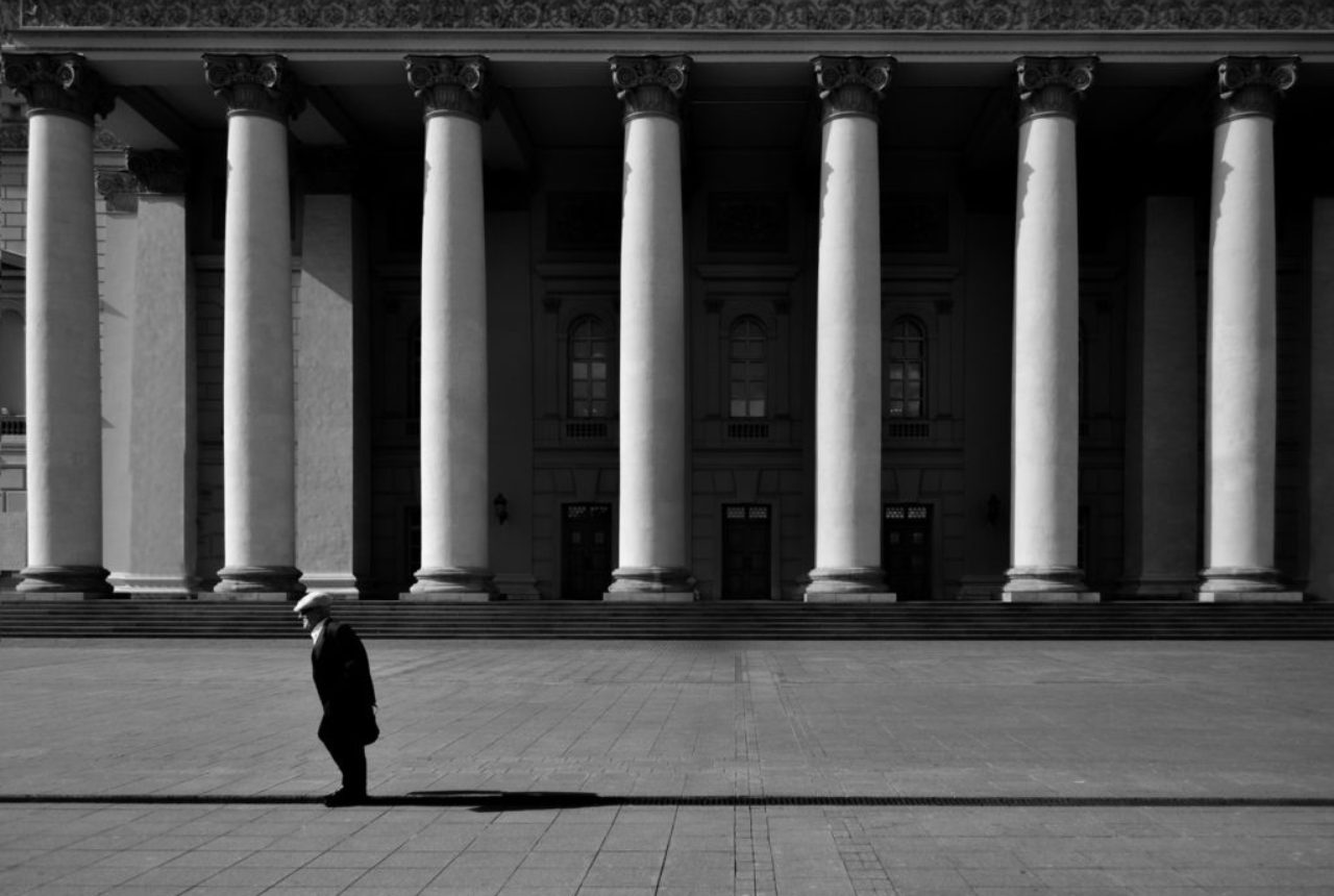 unrecognizable-citizen-against-old-urban-building-with-colonnade